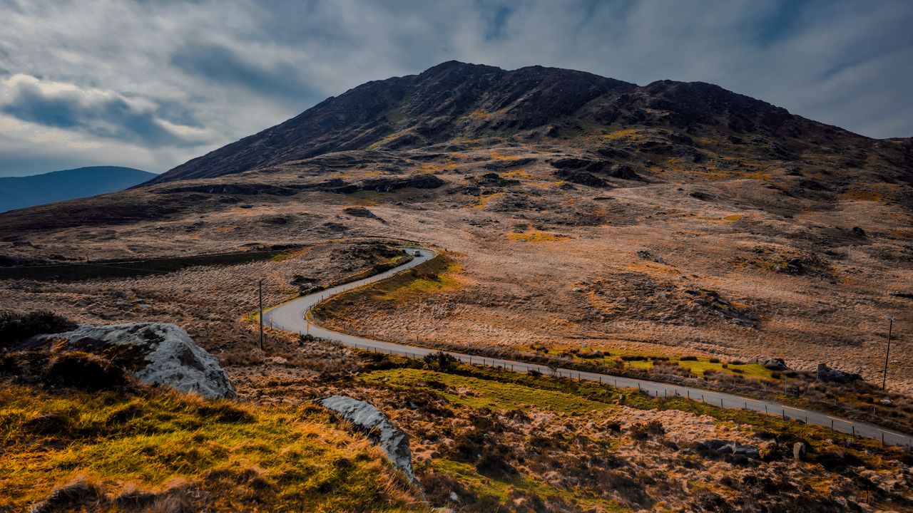 Sweeping view of a winding road through the picturesque Irish landscape with rocky hills.